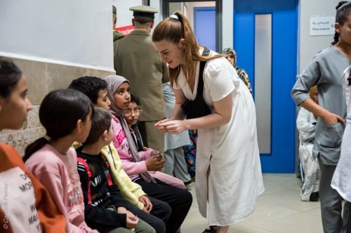 Une bénévole échange avec des enfants dans le couloir d’un centre de consultation.